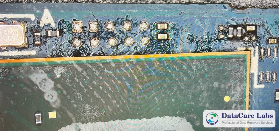 Dried tea film and tide marks on a Samsung 980 SSD board Samsung 980 SSD recovery in Pune: dried tea film around the test pads and tide marks across a chip, before cleaning